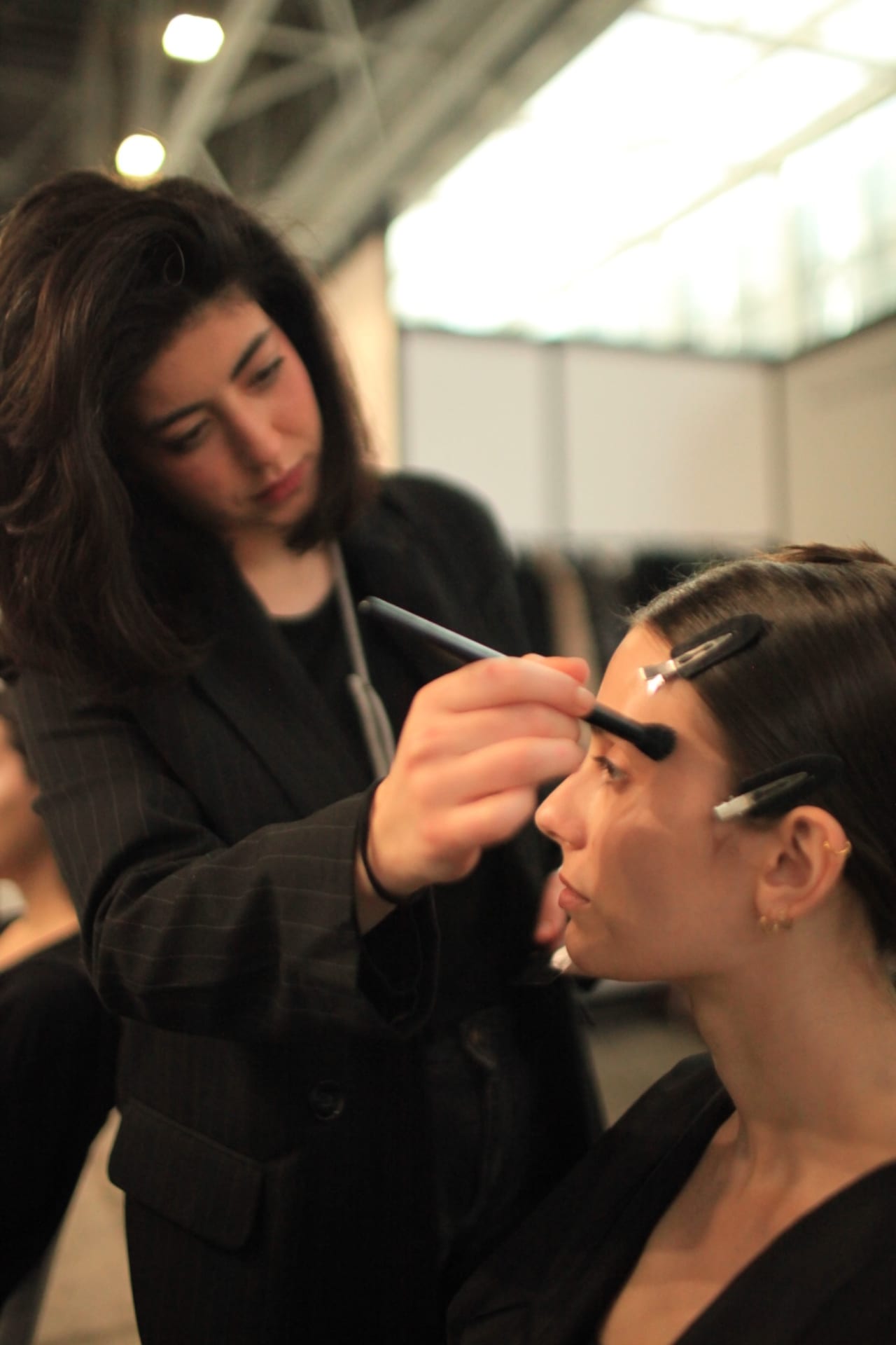 Studente al lavoro sul trucco di una modella durante una lezione in accademia.